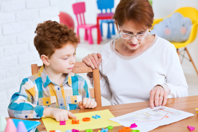 Young boy learning new words playing with colorful letters with his teacher